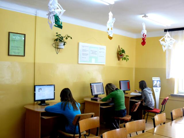 Trzy uczennice siedzą przy stanowiskach komputerowych.