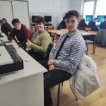 Uczniowie siedzą przy stanowiskach komputerowych
