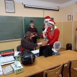 Grupa uczniów w strojach Świętego Mikołaja i Śnieżynek pozują do zdjęcia z nauczycielem.