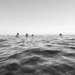 Cztery osoby pływające w morzu.