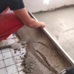 Uczeń wyrównuje beton wylany ma posadzkę