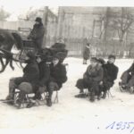 Kulig na sankach i saniach konnych. Grupa osób siedzi na sankach.